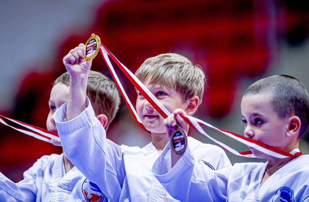Uśmiechnięte dzieci świętujące sukces z medalami Taekwon-Do
